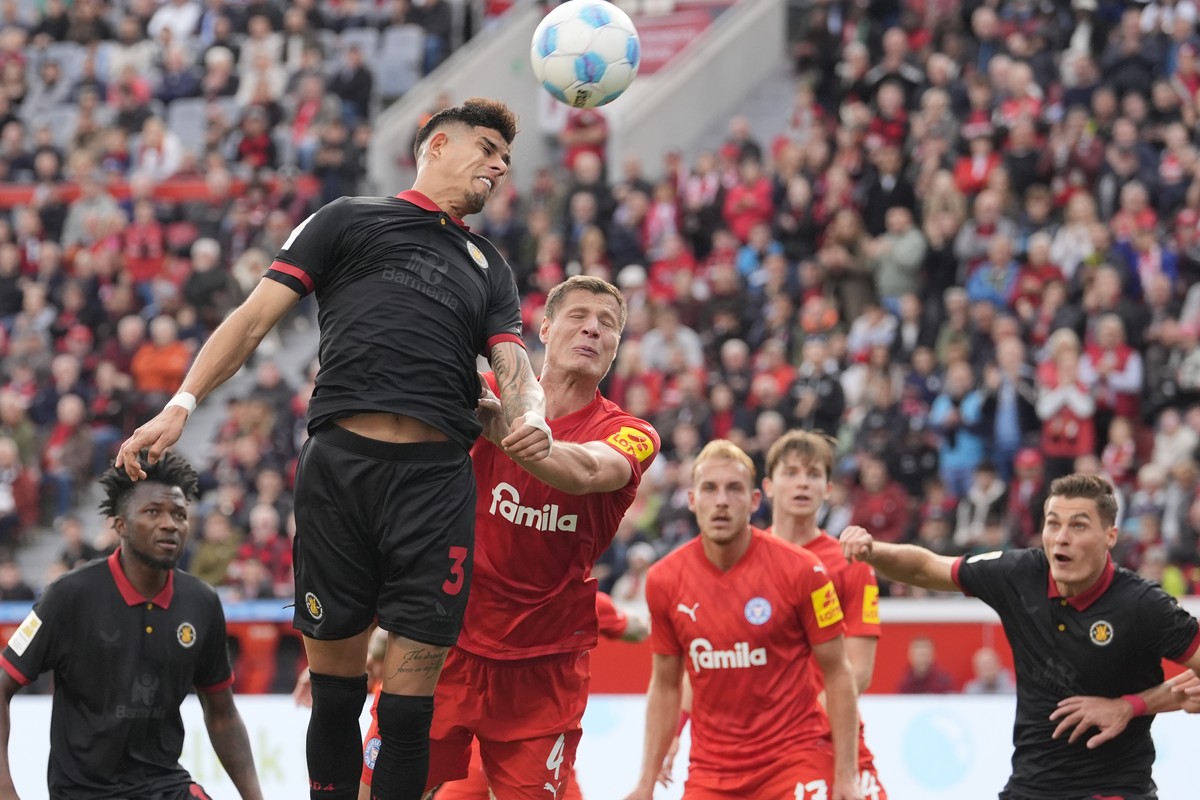 bl, left, and jump for the ball during the German Bundesliga soccer match between Bayer Leverkusen and Holstein Kiel at the BayArena in Leverkusen, Germany, Saturday, Oct. 5, 2024. (AP Photo/Martin Me ...