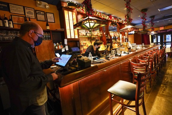 Steve Olsen, left, owner of the West Bank Caf?�, sends a to-go order to the kitchen as Janet Momjian works at the bar in the empty restaurant, Saturday, Jan. 9, 2021, in the Hell's Kitchen neighb ...