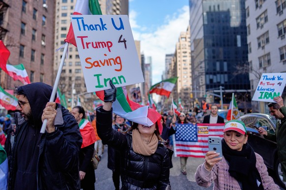 People hold signs thanking President Donald Trump as they take part in a rally in reaction to U.S. and Israeli strikes on Iran and in support of Reza Pahlavi, the exiled son of Irans last shah overth ...