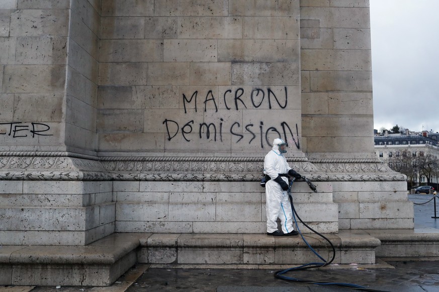A worker is about to clean a graffiti reading &quot; Macron resignation&quot; on the Arc de Triomphe the day after a demonstration, in Paris, Sunday, Dec. 2, 2018. A protest against rising taxes and t ...
