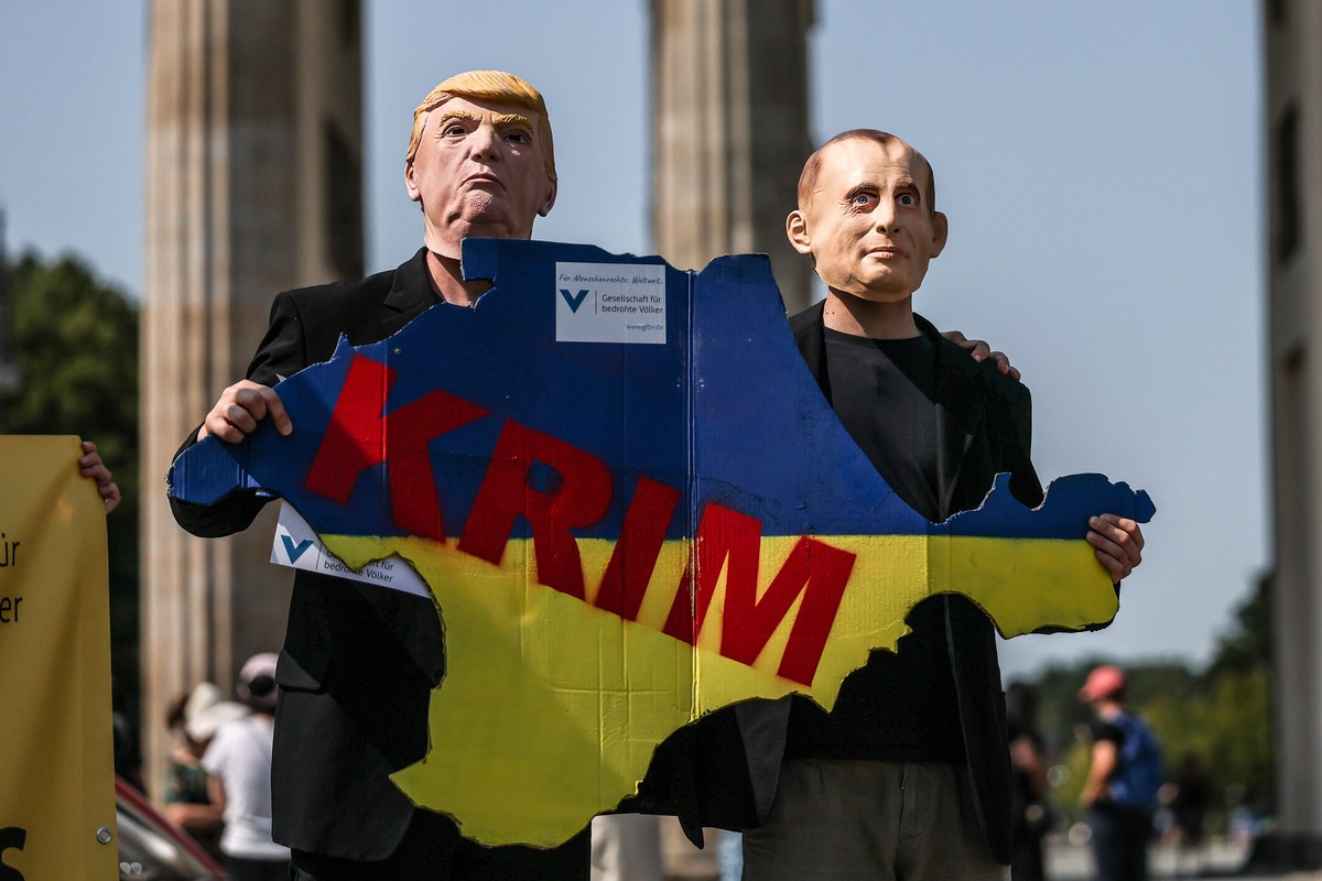 KEYPIX - epa12299731 Activists wearing masks of US President Donald J. Trump (L) and Russian President Vladimir Putin (R) hold a sign in the shape of the Crimean Peninsula in the colors of the Ukraini ...