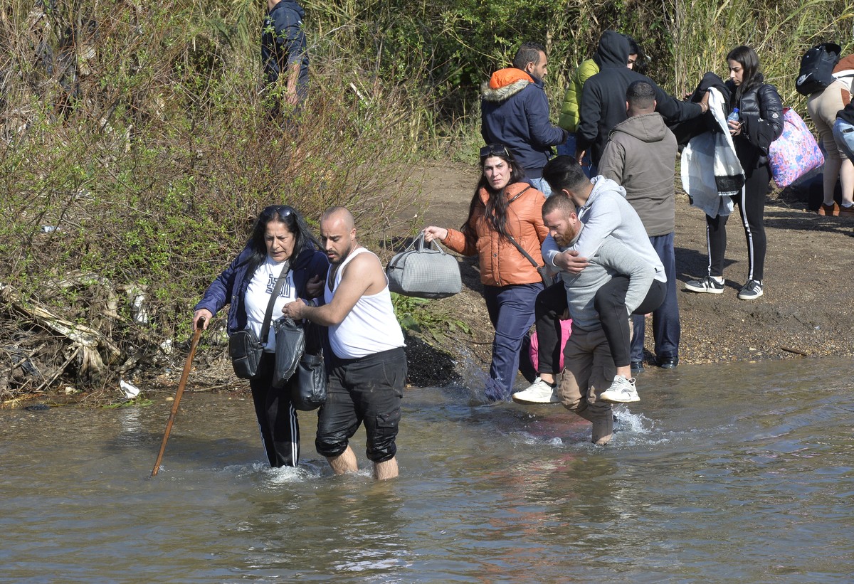 epa11956212 Syrian Alawite refugees who fled from the recent clashes between the Syrian government security forces and the supporters of the former regime, cross Al nahr Al Kabir river that splits Leb ...