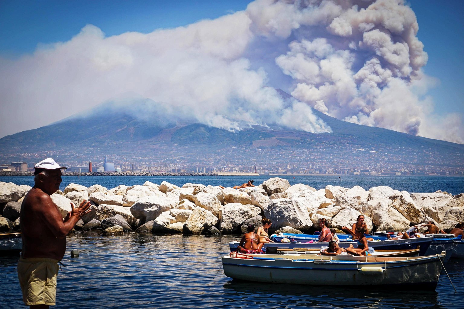 epa06081178 A general view over the city as smoke billows from fires around Mount Vesuvius volcano in Naples, Italy, 11 July 2017. Fires continue to rage after they broke out on 05 July around the act ...