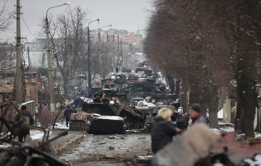 People look at the gutted remains of Russian military vehicles on a road in the town of Bucha, close to the capital Kyiv, Ukraine, Tuesday, March 1, 2022. Russia on Tuesday stepped up shelling of Khar ...