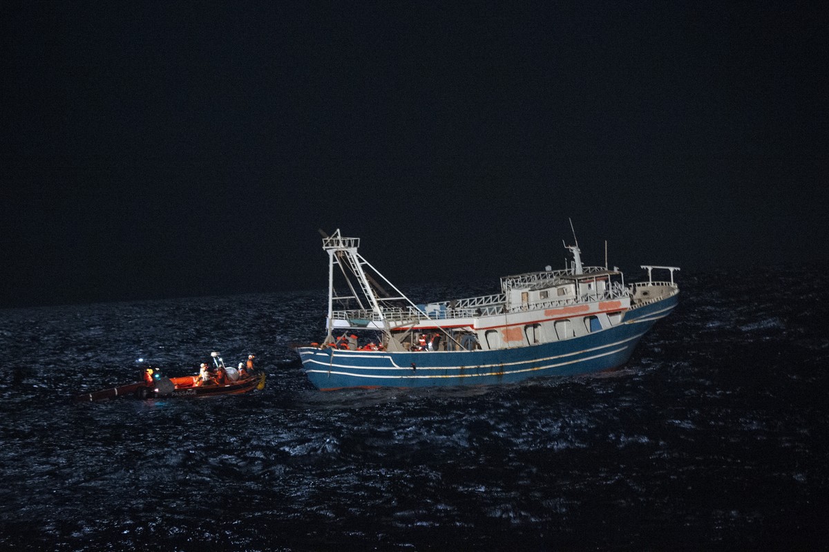 The crew of the rescue boat Geo Barents approach on a dinghy a fishing boat in the international waters off the coast of Libya Tuesday, April 4, 2023. Some 440 refugees from Pakistan, Bangladesh, Egyp ...