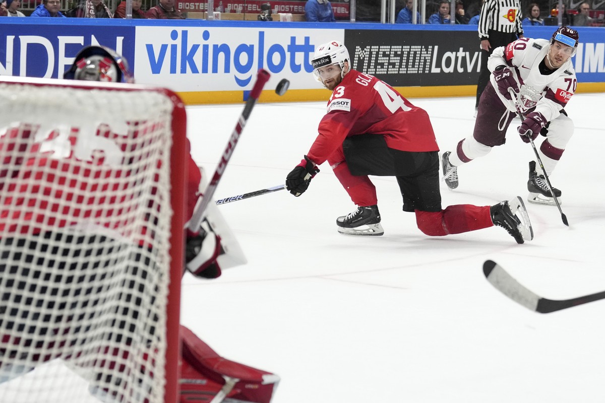 Miks Indrasis of Latvia, right, fights for a puck with Andrea Glauser, center, and goalie Joren Pottelberghe of Switzerland during the group B match between Latvia and Switzerland at the ice hockey wo ...