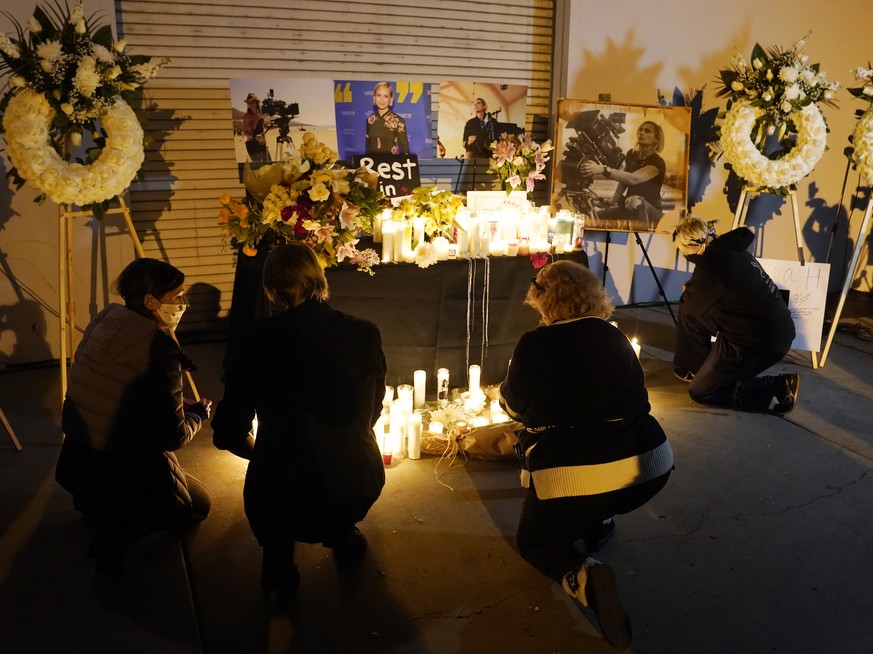 Attendees kneel at a candlelight vigil for the late cinematographer Halyna Hutchins, pictured in photographs, Sunday, Oct. 24, 2021, in Burbank, Calif. A prop firearm discharged last Thursday by actor ...