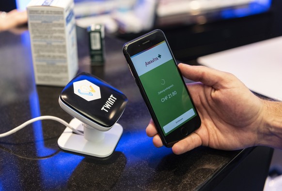 [Staged Picture] A person uses the Twint cashless payment system via app on a smartphone at a Twint beacon terminal in an Amavita pharmacy in Berne, Switzerland, on May 2, 2018. (KEYSTONE/Christian Be ...