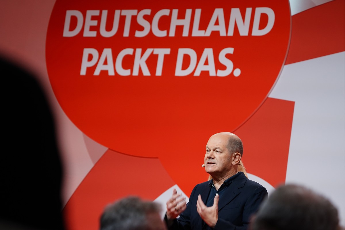 epa10288180 German Chancellor Olaf Scholz gestures in front of the writing 'Deutschland packt das.' (lit.: Germany can manage it.) as he speaks in a town hall format at the debate convention ...