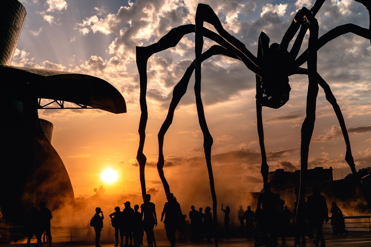 RECORD DATE NOT STATED Sunset next to the Guggenheim Museum in Bilbao, a group of silhouettes walk near the sculpture Maman *** Sonnenuntergang n