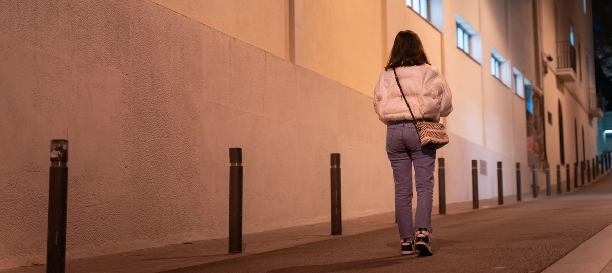 Beautiful young woman from the back walking in the night city street alone. Danger street stalker. model released
