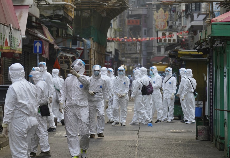 Government investigators wearing protective suits, gather in the Yau Ma Tei area, in Hong Kong, Saturday, Jan. 23, 2021. Thousands of Hong Kong residents were locked down Saturday in an unprecedented ...