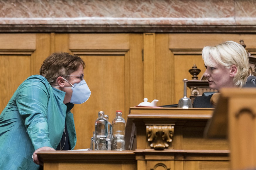 Magdalena Martullo-Blocher, SVP-GR, links, eine Atemschutzmaske tragend, diskutiert mit der Ratspraesidentin Isabelle Moret, FDP-VD, am ersten Tag der Fruehlingssession der Eidgenoessischen Raete, am ...