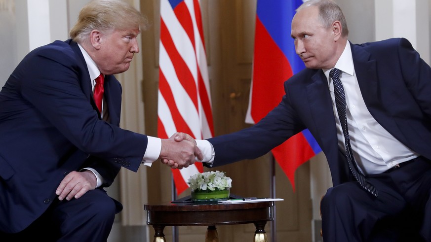 In this July 16, 2018, photo, U.S. President Donald Trump, left, and Russian President Vladimir Putin, right, shake hands at the beginning of a meeting at the Presidential Palace in Helsinki, Finland. ...