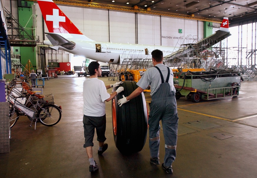 ARCHIVBILD ZUM STELLENABBAU BEI SR TECHNICS, AM MONTAG, 9. APRIL 2018 - Angestellte von SR Technics rollen am Montag, 7. Juli 2003, im Hangar in Glattbrugg einen Reifen fuer ein Swiss Flugzeug durch d ...