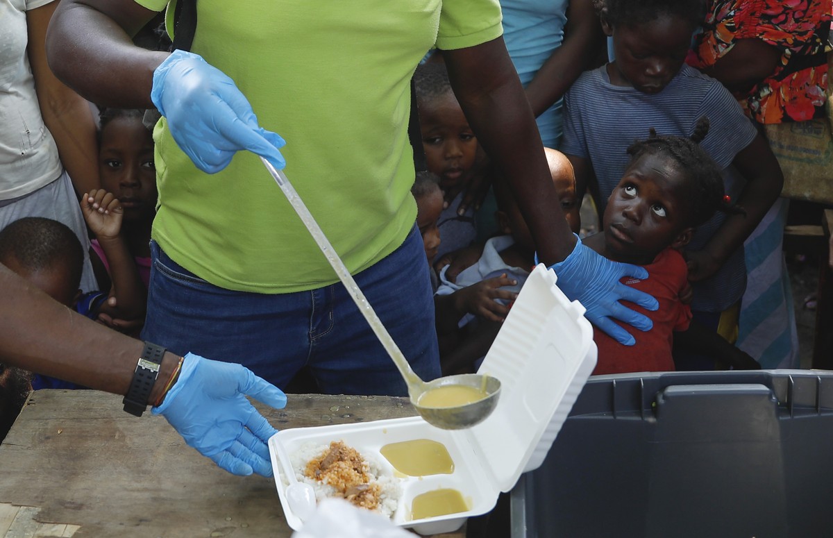FILE - A server ladles soup into a container as children line up to receive food at a shelter for families displaced by gang violence, in Port-au-Prince, Haiti, March 14, 2024. More than 360,000 have  ...