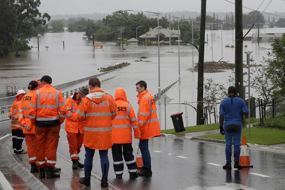 State Emergency Service personnel gather at the entrance to a submerged bridge surrounded by water from the flooded Hawkesbury River in Windsor, northwest of Sydney, New South Wales, Australia, Monday ...