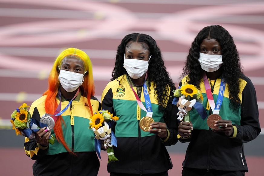 epa09385021 Gold medalist Elaine Thompson-Herah (C), silver medalist Shelly-Ann Fraser-Pryce (L) and bronze medalist Shericka Jackson (R) of Jamaica during the medal ceremony for the women&#039;s 100m ...