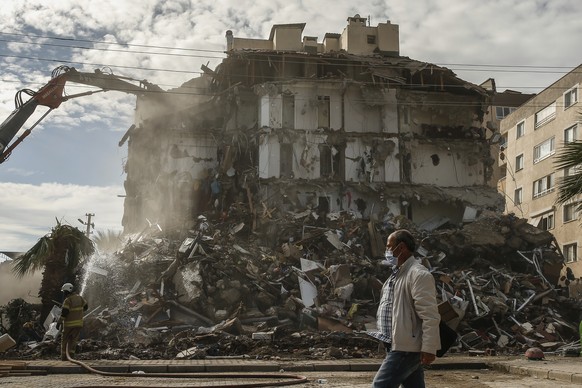 A man walks past the debris of a collapsed building, in the coastal city of Izmir, Turkey, Monday, Nov. 2, 2020. Rescue teams continue ploughing through concrete blocs and debris of collapsed building ...