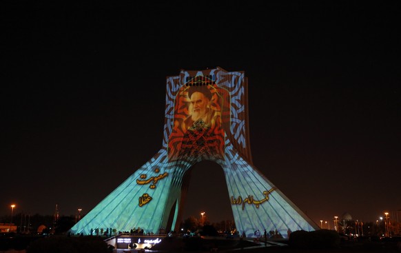 epa09994560 Azadi (Freedom) tower is illuminated with pictures of Iranian late supreme leader Ayatollah Ruhollah Khomeini during a ceremony organized by the city municipality on the occasion of 33rd d ...