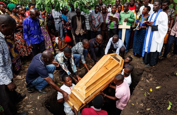 epaselect epa10698325 People lower a coffin into a grave during the funeral for one of the victims of an attack at a school, in Mpondwe, Uganda, 18 June 2023. At least 37 people were killed in an atta ...