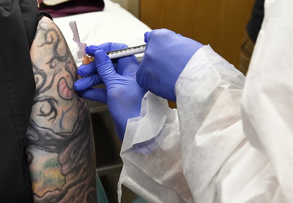 FILE - In this July 27, 2020, file photo, Nurse Kathe Olmstead, right, gives a volunteer an injection as a study of a possible COVID-19 vaccine, developed by the National Institutes of Health and Mode ...