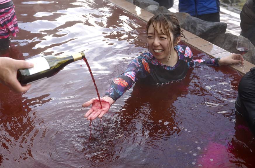 epa11732339 A sommelier pours 2024 Beaujolais Nouveau wine as people bathe in a red-colored hot water bath on the day of the Beaujolais Nouveau official release at Hakone Kowakien Yunessun hot spring  ...