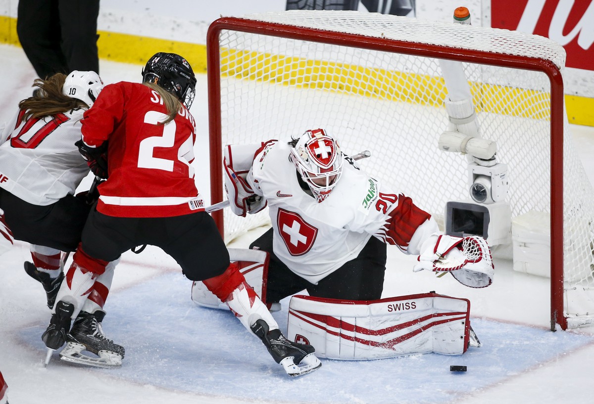 Switzerland goalie Andrea Braendli, right, grabs for the puck as Canada's Natalie Spooner looks on during the third period of an IIHF women's hockey championships semifinal in Calgary, Alber ...