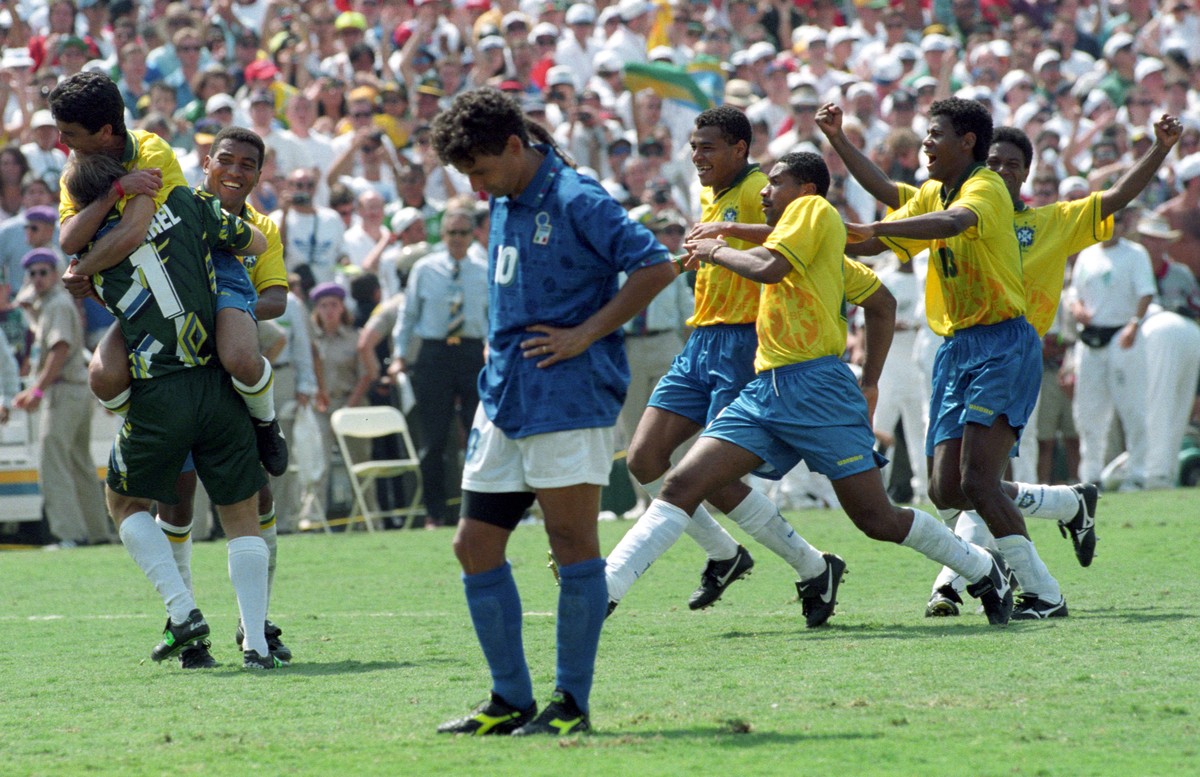 Brazilian striker Bebeto leaps into the arms of goalkeeper Claudio Taffarel (L) as Italy's Roberto Baggio (C) stares at the ground after missing the penalty kick which cost his team the World Cup ...