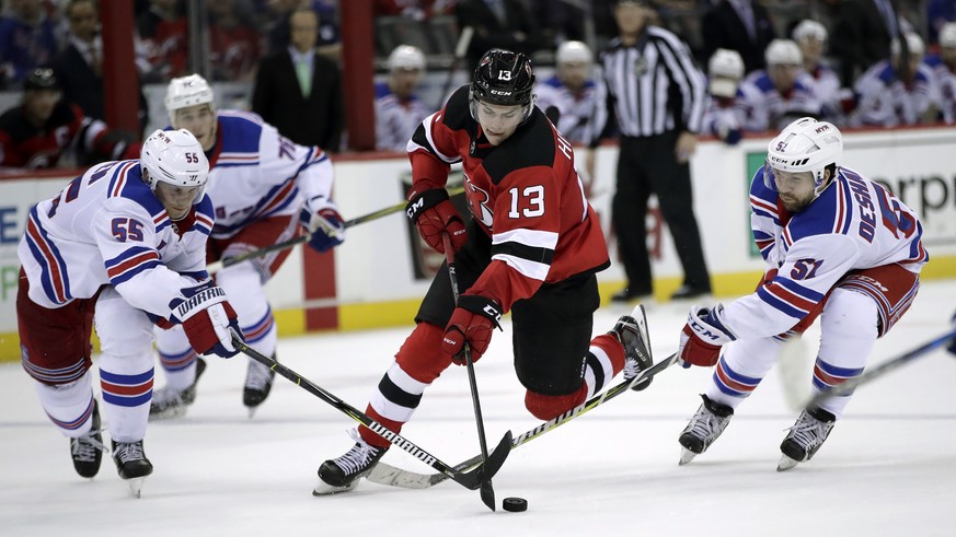 New Jersey Devils center Nico Hischier (13), of Switzerland, skates with the puck as New York Rangers defenseman Nick Holden (55) and center David Desharnais (51) defend during the second period of an ...