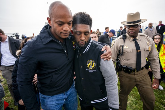epa11244658 Maryland Governor Wes Moore (L) and Baltimore Mayor Brandon Scott (C) react following a press conference at the scene of the Francis Scott Key Bridge collapse in Baltimore, Maryland, USA,  ...