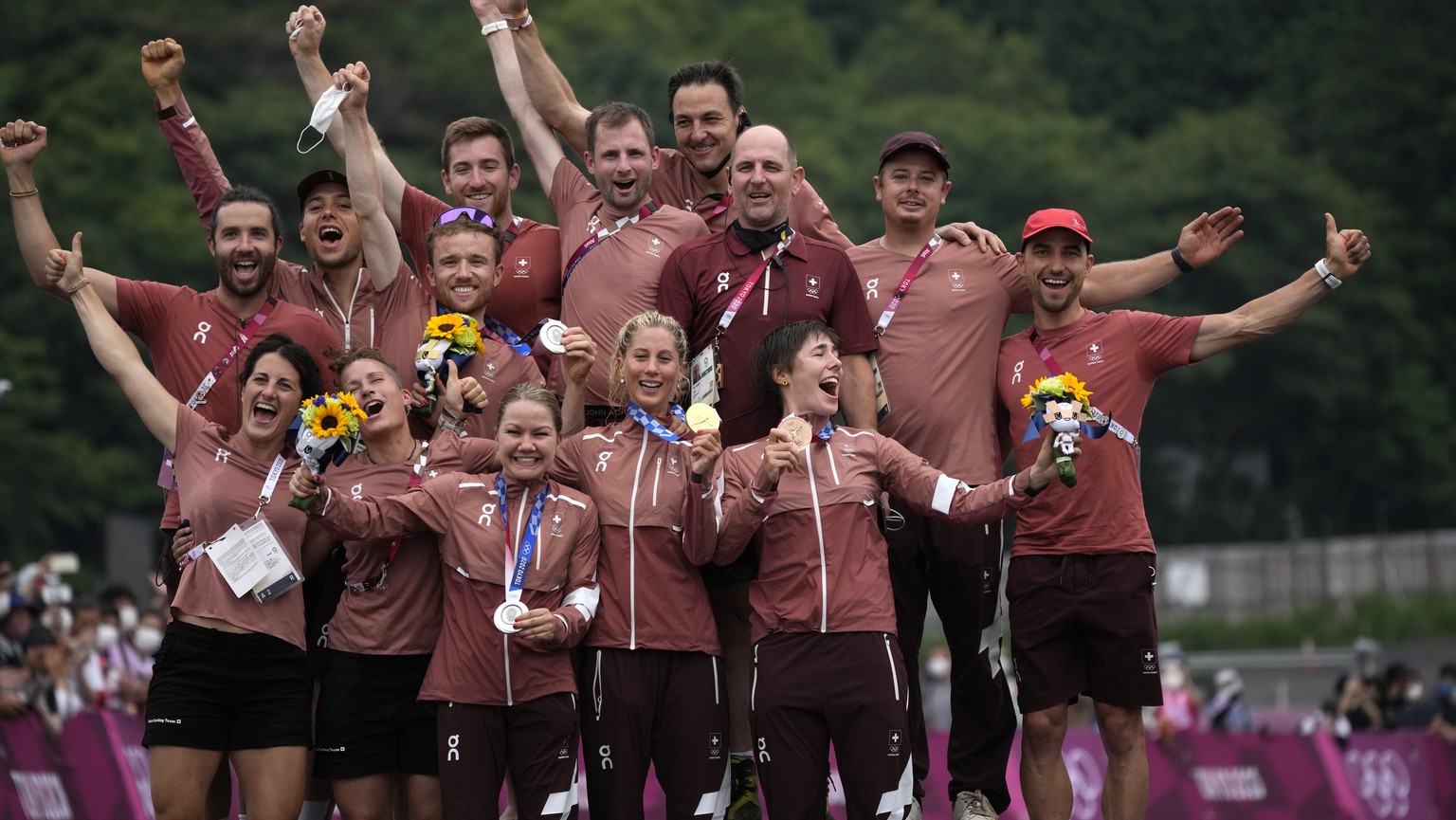 Switzerland&#039;s gold medalist Jolanda Neff, center front, silver medalist Sina Frei, left front, and bronze medalist Linda Indergand, right front, pose with their medals and their team during a med ...