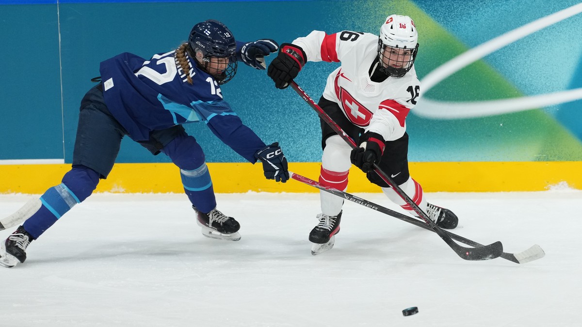 Switzerland's Nicole Vallario (16) passes the puck past Finland's Sanni Vanhanen (12) in the second period during a preliminary round match of women's ice hockey at the 2026 Winter Olym ...