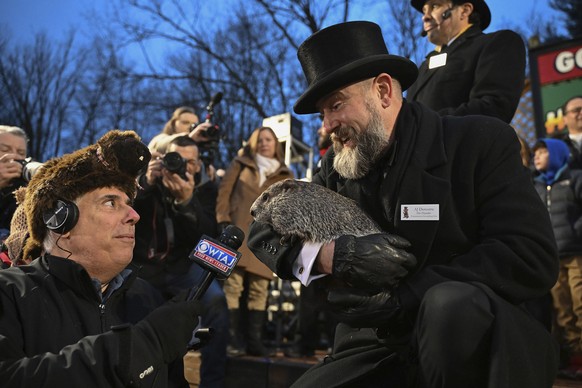 Groundhog Club handler A.J. Dereume holds Punxsutawney Phil, the weather prognosticating groundhog, as he is interviewed by a reporter during the 138th celebration of Groundhog Day on Gobbler&#039;s K ...