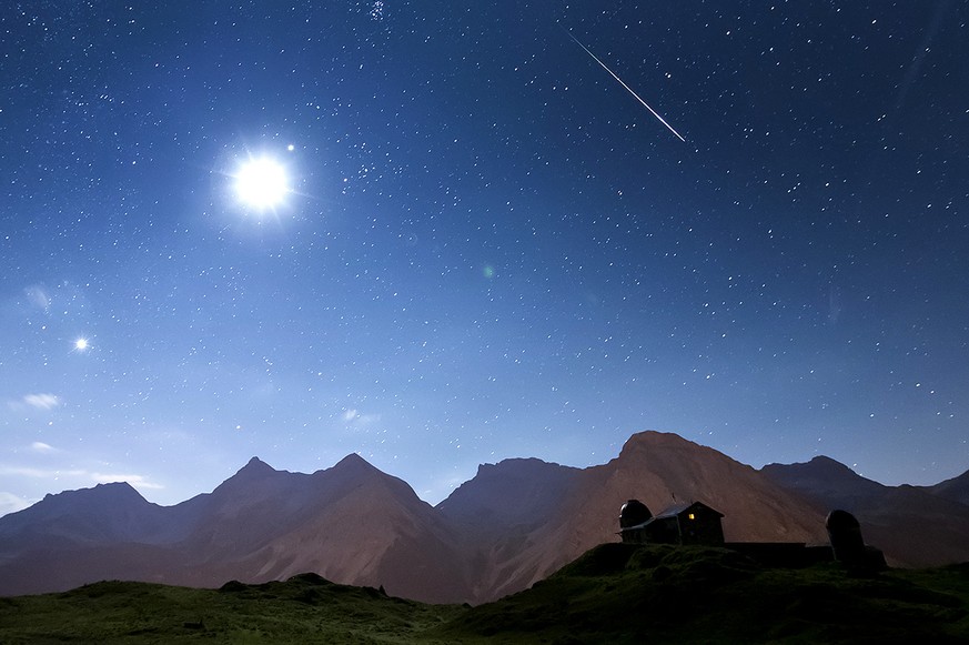 Eine sehr helle Sternschnuppe leuchtet am Nachthimmel ueber der Sternwarte in Arosa, in der Nacht auf Sonntag, 12. August 2012. Links scheint der Mond. Hinten die Berge Medergerflue, Tiejerflue, Furka ...