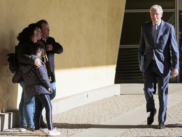 European Union chief Brexit negotiator Michel Barnier, right, walks by people posing for a photo on his way to an EU General Affairs ministers from EU headquarters in Brussels, Tuesday, Feb. 25, 2020. ...