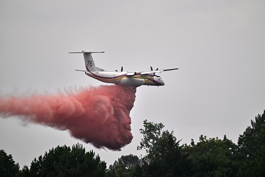 A De Havilland Canada DHC-8-400 Dash 8 operated by the French civil defense agency drops fire retardant as wildfires rage near Marcheprime, outside Bordeaux, France, Monday, July 27, 2026. (AP Photo/E ...