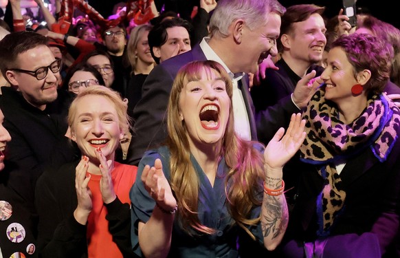 epaselect epa11919011 Heidi Reichinnek (C), top candidate for the Left Party (Die Linke), along with co-leaders Jan van Aken (C-back) and Ines Schwerdtner (2-L), reacts to initial results during the L ...
