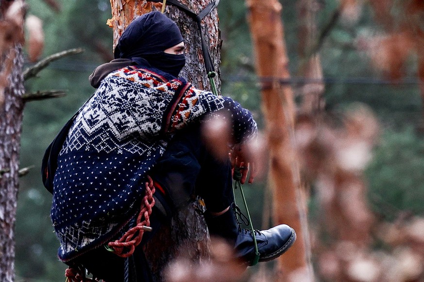 epa11200363 An activist climbs a tree during a protest by environmental activists against plans to cut down the forest to extend the Tesla Gigafactory in Gruenheide, near Berlin, Germany, 05 March 202 ...