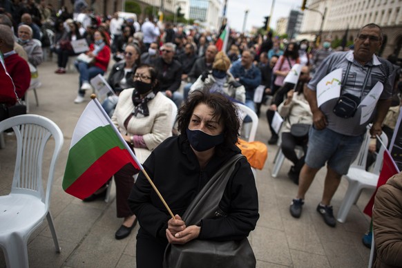 epa08439149 A woman wearing a face mask holds up a Bulgarian national flag during an anti-government protest in front of the building of the Council of Ministers in Sofia, Bulgaria 23 May 2020. Hundre ...