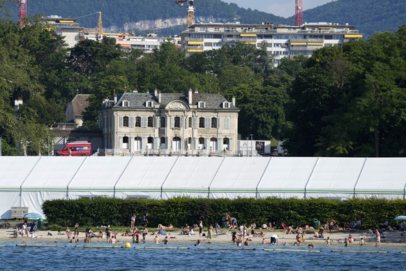 People swim on the shores of Lake Geneva in front of a tent that was set up as a media center opposite the &#039;Villa La Grange&#039; the venue for the upcoming meeting between US President Joe Biden ...