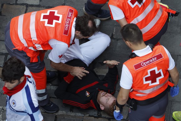 epa13109840 Red Cross members attend to one of the runners after the runner was gored by bulls from the Jandilla ranch during the final bull run of the San Fermin festival in Pamplona, Navarra, northe ...