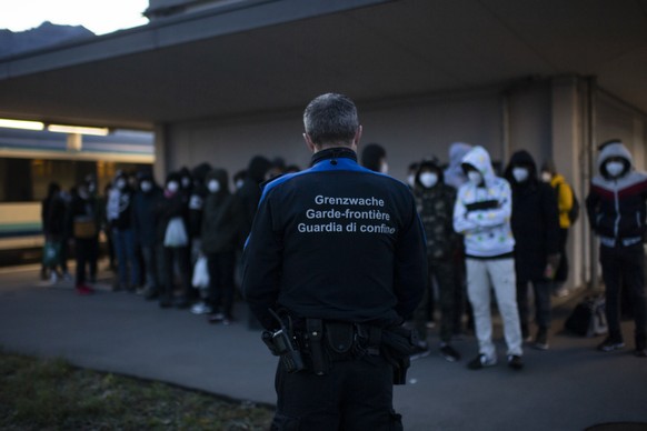 Grenzwaechter bringen Fluechtlinge aus einem Zug aus Wien zur Kontrolle, am Freitag, 19. November 2021, am Bahnhof in Buchs. Seit dem Sommer gelangen vermehrt afghanische Fluechtlinge an den Grenzbahn ...