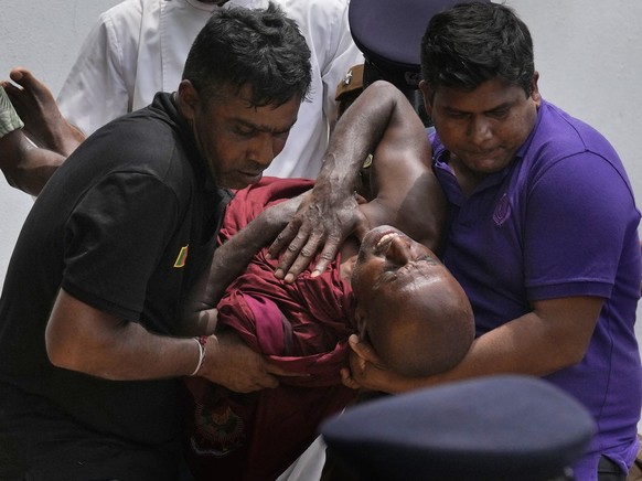 An injured Sri Lankan Buddhist monk is being carried away who among many other anti-government protesters were injured after attacked by government supporters outside prime minister Mahinda Rajapaksa& ...