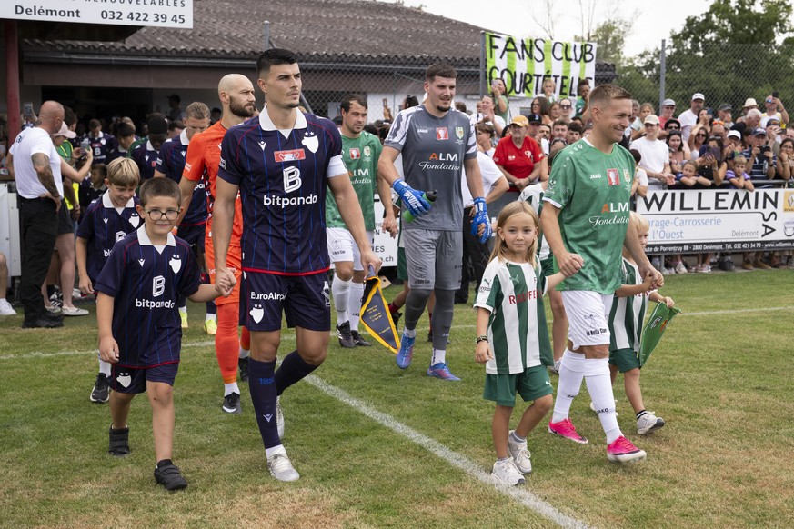 Flavius Daniliuc (FCB), gauche, Tom Villemin (FC Courtetelle), droite, et leurs coequipiers entrent sur le terrain lors de la rencontre de 32eme de finale de la coupe de suisse de football entre le FC ...