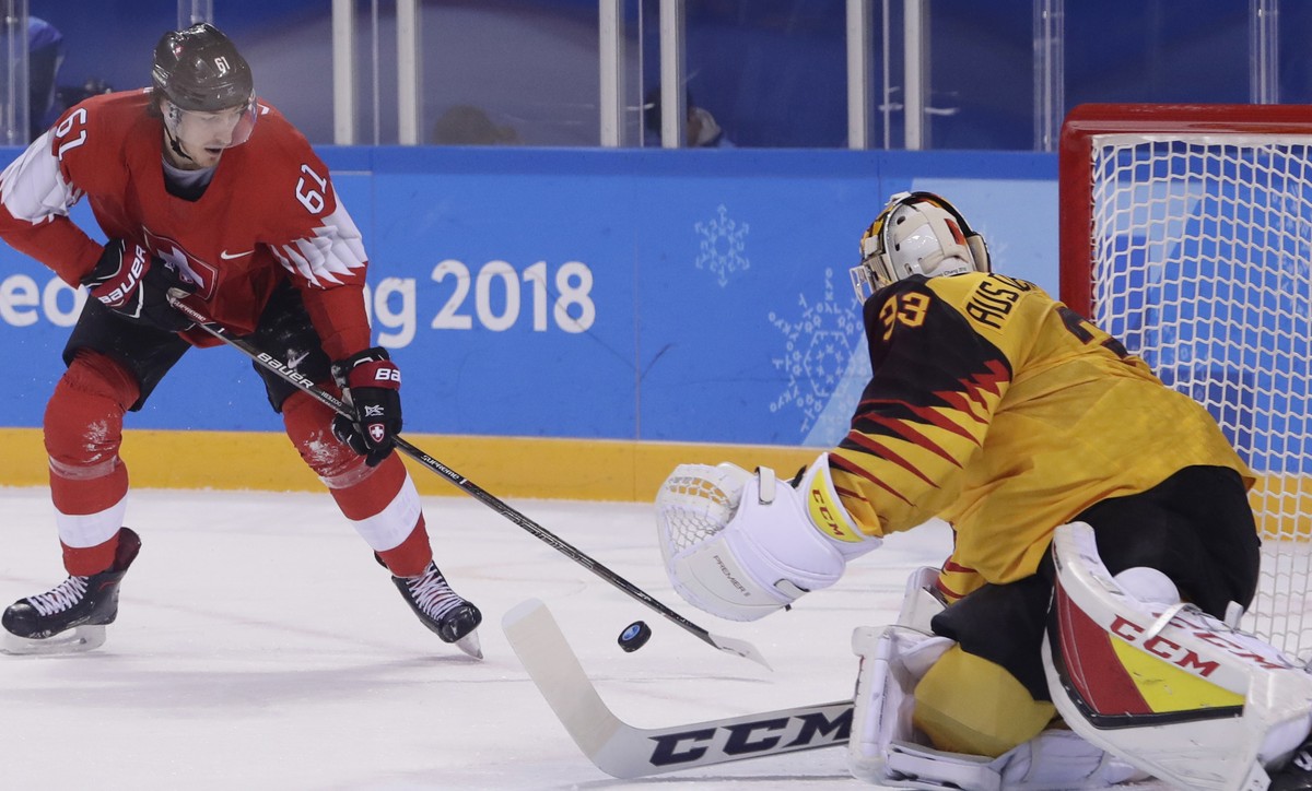Den Birken Danny Aus, of Germany, stops a shot on the goal from Fabrice Herzog, of Switzerland, during the first period of the qualification round of the men's hockey game at the 2018 Winter Olym ...