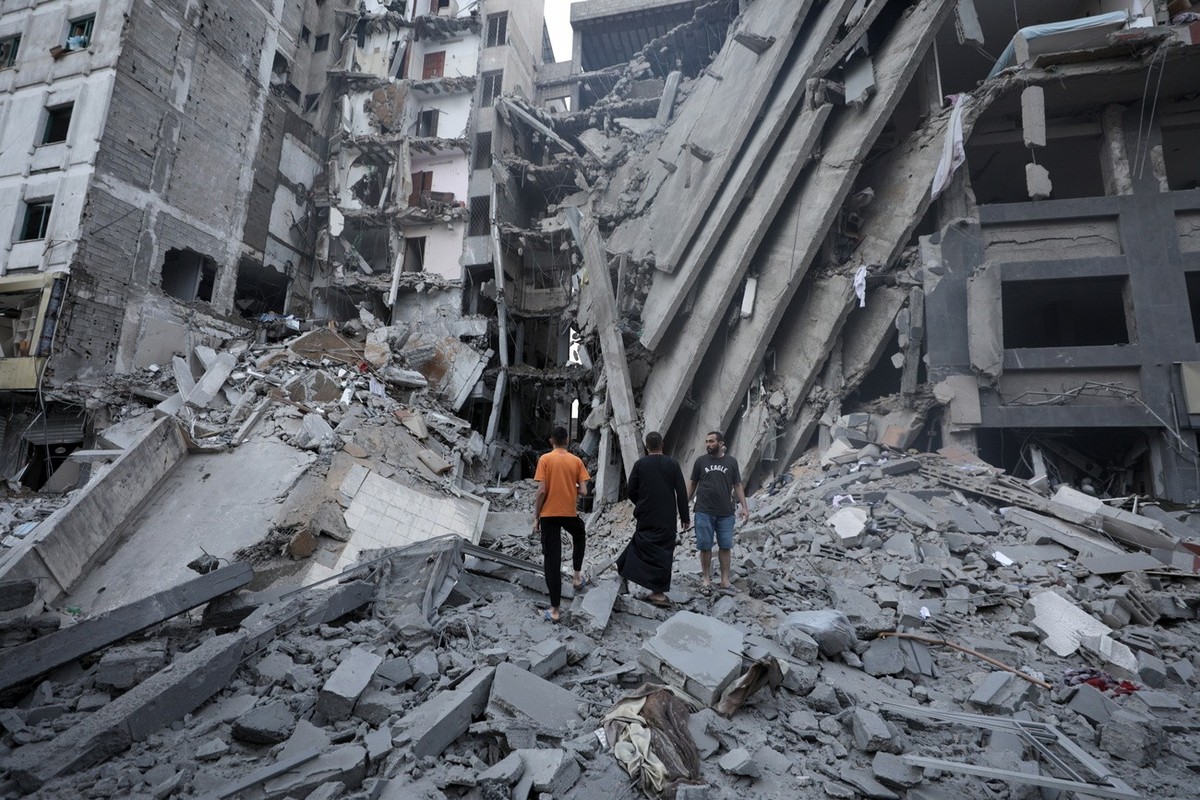 epa10907925 Palsetinians inspect the damage in the surrounding of the destroyed National Bank building following Israeli air strikes, in Gaza City, 08 October 2023. The air strikes in retaliation for  ...