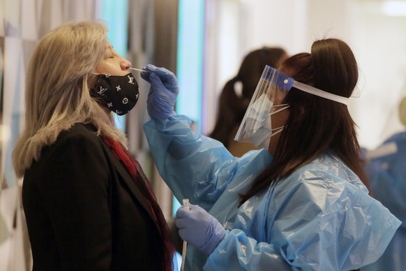 epa08900040 Mildred Barberena (L) of Encino gets swabbed for a Coronavirus test before she can get on a flight to Guatemala in Terminal 2 at Los Angeles International Airport in Los Angeles, Californi ...