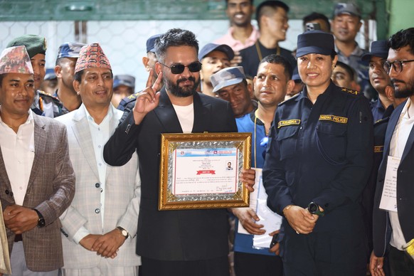Balendra Shah, foreground, former mayor of Kathmandu Metropolitan City and prime ministerial candidate of the Rastriya Swatantra Party, receives his victory certificate after defeating former Prime Mi ...