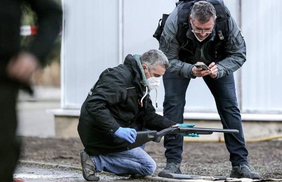 epa09706819 Police officers examine a weapon near the crime scene at the Heidelberg University in Heidelberg, Germany, 24 January 2022. A man with long-barrelled firearm had opened fire at students in ...